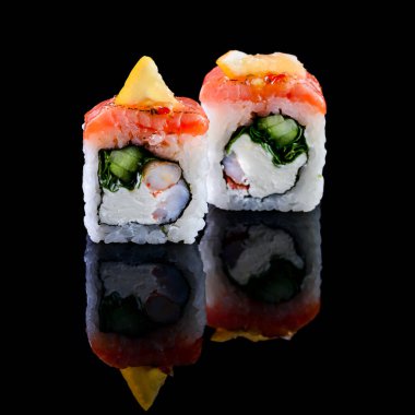 Asya mutfağı kavramı. Japon menü kafesi, restoranı ve suşi barı için siyah arka planda farklı doldurulmuş iki rulo suşi. Yansıması olan iki suşi rulosu.