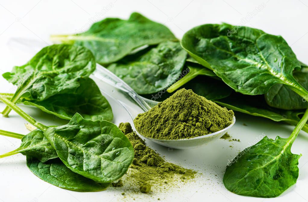 dry spinach powder on white background. Green Powder. Could be any Green Super Food. Perhaps spirulina, chorella, barley grass, dried broccoli, spinach.