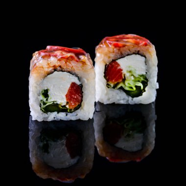 Asya mutfağı kavramı. Japon menü kafesi, restoranı ve suşi barı için siyah arka planda farklı doldurulmuş iki rulo suşi. Yansıması olan iki suşi rulosu.
