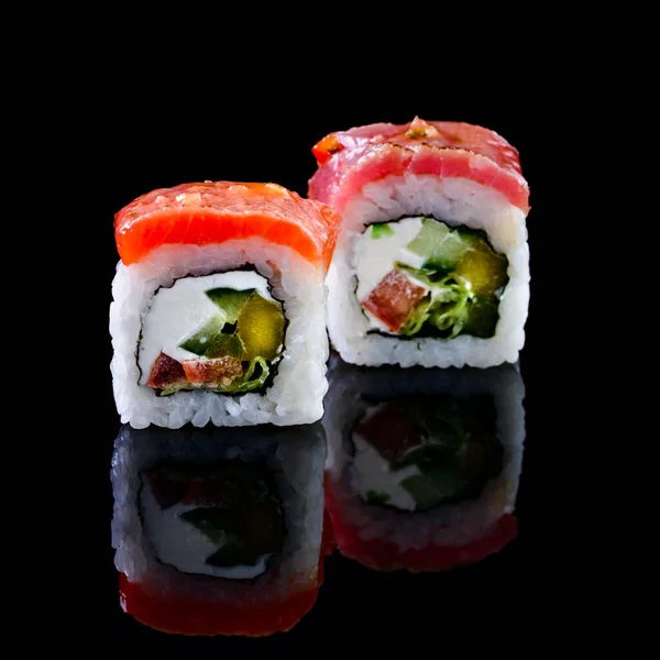 Concept of Asian cuisine. Two rolls of sushi with different fillings on a black background for Japanese menu cafe, restaurant, sushi bar. two sushi rolls couple isolated with reflection