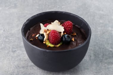 Taze yabanmersinli çikolatalı tatlı ve gri arka planda yaban mersini kasesi. Kahvaltıda tatlı.