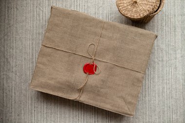Keten iple bağlanmış bir kutu ve masada bir mürekkep mührü var. Keten kumaşla mühürlenmiş bir paket.