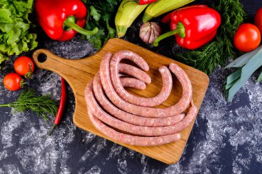 Tahtada taze çiğ sosis, baharatlı ve sebzeli çiğ sosis. Üstten bakıldığında taze yapılmış çiğ sosisli kasaplar. Metnin için boş yer