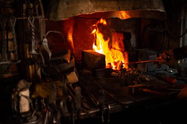 Demirci kil fırında sıcak kömürlerin üzerinde kaleyi tutuyor. Demirci, demir kılıcı ısıtıyor demirhane demirhanesi, demircinin elleri kızgın demir ocağında çelik tutuyordu.