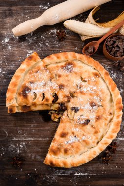 Hamur işleri, cevizli pasta ve ahşap zemin üzerinde pudra şekerli muz. Muz ve çikolatalı ev yapımı kek.