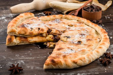 Hamur işleri, cevizli pasta ve ahşap zemin üzerinde pudra şekerli muz. Muz ve çikolatalı ev yapımı kek.