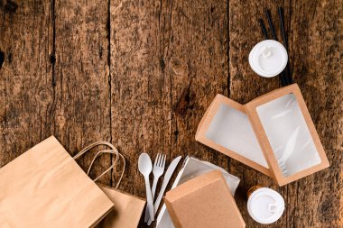 Eko kağıt sofra takımı. Kağıt bardaklar, tabaklar, torbalar, fast food kutuları, teslimat için kutu. Geri dönüşüm konsepti. Sıfır kayıp. Çevre dostu yiyecek kutuları ahşap arka planda fotokopi alanı ile birlikte