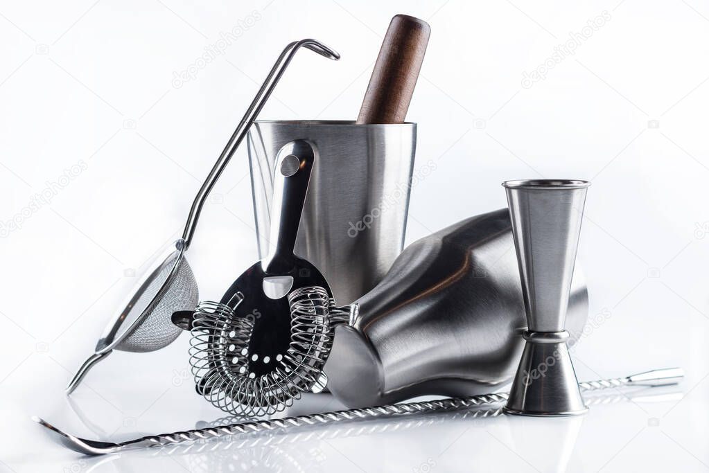 Cocktail shaker, strainer and long cocktail spoon and other bartender equipment isolated on white, steel bartender accessories