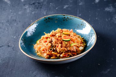 Geleneksel Kore yemekleri. Japchae ya da Chapchae denilen soya soslu kızarmış cam şehriye. Siyah kasede domuz etli cam şehriye. Koyu tahta masa üzerinde. En iyi Asya yemekleri.