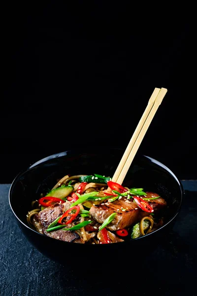 配以金枪鱼和蔬菜的美味面条 背景为深色石料 传统的亚洲风味金枪鱼面 炒面或黑碗里的锅面 — 图库照片