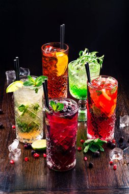 Beş çeşit cin tonik, böğürtlenli, portakallı, limonlu ve nane yapraklı. Kırsal ahşap arka planda gözlüklerle. Yaz alkollü kokteyller ya da soğuk limonatalar.