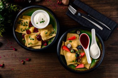 Taze böğürtlenli ravioli, ev yapımı hamur tatlısı, yaban mersini dolgulu vareniki taze böğürtlenli koyu kırsal bir masada.