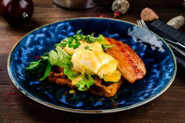 Ekmek üstü haşlanmış yumurta, füme domuz pastırması ve salata. Haşlanmış yumurta, bitki ve pastırmalı sandviç. Yumurtalı Benedict kahvaltısı. Yakın plan. Yumurtalı tost.