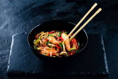 Asyalı udon eriştesi ve kaplan karidesi. Arka planda siyah kâse. Çubuklu Tayland eriştesi.