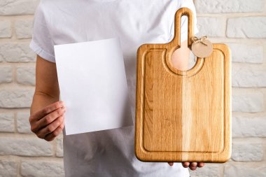 Kadın El Tutma Tahtası, temiz beyaz kağıt ile kesme tahtası, kadınların elindeki tahta kesme tahtası, metin için fotokopi alanı ile yakın plan. Mönü için odunu kapat ve tasarımı taklit et.