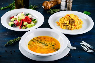 Üç çeşit çorba, ikinci tabak ve salata, ahşap masada servis edilen üç çeşit menü, üç öğünden oluşan iş yemeği seti.