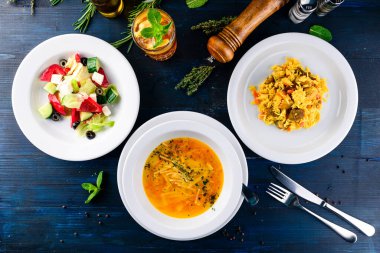 Üç çeşit çorba, ikinci tabak ve salata, ahşap masada servis edilen üç çeşit menü, üç öğünden oluşan iş yemeği seti.