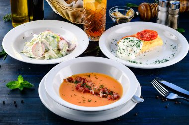 Üç çeşit çorba, ikinci tabak ve salata, ahşap masada servis edilen üç çeşit menü, üç öğünden oluşan iş yemeği seti.