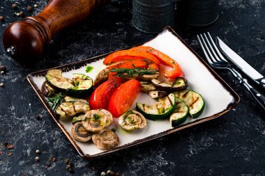 Tabağa farklı ızgara sebzeler koyun. Vejetaryen barbekü piknik seti, sıcak sebze salatası. Tabakta ızgara sıcak sebze, kabak, biber ve mantar.