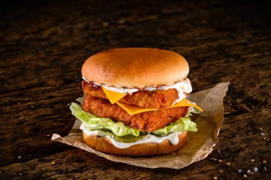 Peynirli, bol yağda kızartılmış ve ahşap bir masada siyah arka planda fotokopi alanı olan çift katlı leziz hamburgerler. Eski ahşap bir arka planda duble burger.