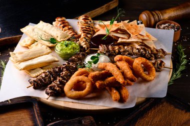 Tavuk kebabı, şiş kebap ve abur cubur soğan halkaları ve ahşap tabakta atıştırmalıklar.