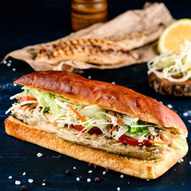 Füme uskumru etli buğday balığı burgeri, peynir, domates, salatalık ve marul. Uskumru ve taze salatalı büyük balıklı sandviç. Balik ekmek - Türk fast food