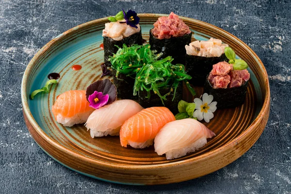 Various kinds of sushi roll set served on black stone. Japanese food. Sushi Set nigiri, rolls, gunkan and sashimi served in traditional Japan Sushioke round plate