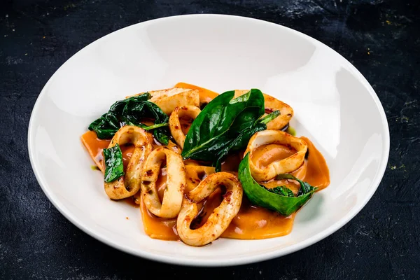 Sağlıklı Akdeniz yemeği için domates soslu kalamar halkaları, mürekkep balığı halkaları. Sebzeli deniz ürünleri güveci. Kalamar, İtalyan yemek pişirme kavramını ortaya çıkarır.