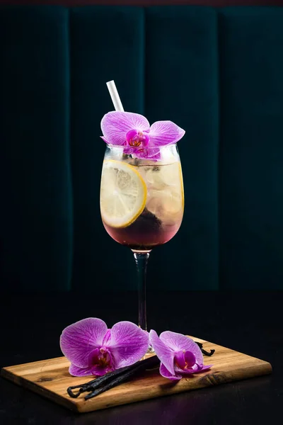 Summer tropical cocktail wine champagne decorated pink orchid flowers. cocktail with lemon and ice, decorated with an orchid
