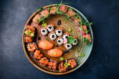 Siyah taşla servis edilen çeşitli suşi çeşitleri. Japon yemeği. Suşi seti nigiri, rulo, gunkan ve sashimi geleneksel Japon suşi tabakasında servis edilir.