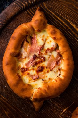 Peynirli ve pastırmalı Adjarian Khachapuri. Koyu ahşap arka planda peynirli ve pastırmalı Gürcü Khachapuri.