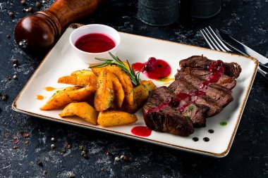 Kızarmış patatesli kaburga bifteği, sarımsak sosu ve şifalı otlar. Tabakta pirzola.