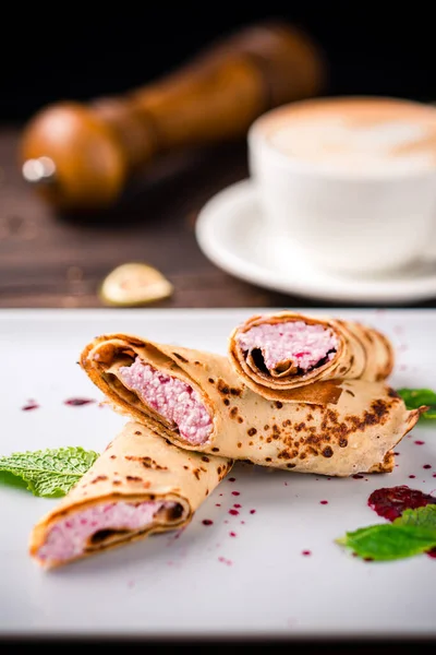 Kahvaltıda süzme peynir ve kahveyle doldurulmuş krepler, ahşap masada süzme peynirli krepler, lezzetli bir kahvaltı.