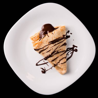 Çikolatalı ince bir krep siyah arka planda izole edilir, çikolata soslu krepler. Koyu arkaplanda çikolata soslu krepler