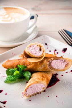 Ahşap arka planda süzme peynir ve bir fincan kahveyle dolu krepler. Kahvaltı krepleri, süzme peynir ve kahve.