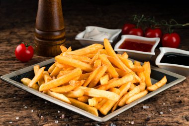 Patates kızartması, patates kızartması ve ketçap. Sağlıksız yemek geçmişi, ahşap arka plana yakın çekim.