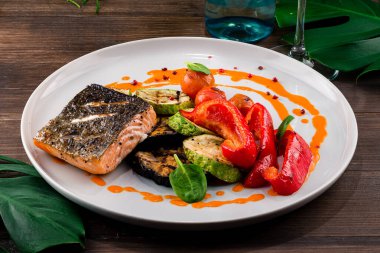 ızgara somon ve ızgara sebze biber, patlıcan, kabak, sıcak ve baharatlı fileto kırmızı balık. Izgara biftek somonu mu yoksa ızgara kırmızı biberli alabalık mı? Sağlıklı yiyecekler, deniz ürünleri ve sebzeler.