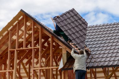 Çerçevenin çatısını ustalar yapar. Yeni evin çatısında da metal. Çatı inşaatı. Ahşap yapı