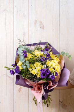 Çok hoş bir genç bayan elinde büyük ve güzel pofuduk bir buket, kesilmiş bir fotoğraf, ahşap arka planda bir kadının elinde güzel bir buket.