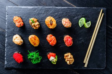 Farklı türde balıklı Gunkan Maki Sushi seti (somon, deniz tarağı, levrek, yılan balığı, karides) ve siyah arka planda havyar. Suşi menüsü. Japon yemek suşisi silah seti.