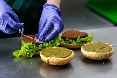 Tanımlanamayan şef iştah açıcı hamburgerler hazırlıyor.