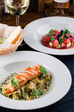 Somon ve krema soslu makarna. Somon ve havyarlı makarna bir bardak beyaz şarapla birlikte beyaz bir tabakta.