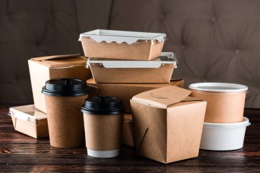 Yemek dağıtım araçları için eko sofra takımını hazırlayın. Eko kağıt sofra takımı. Kağıt bardaklar, tabaklar, torbalar, fast food kutuları, tahta arka planda teslimat için kutular. Geri dönüşüm konsepti. Sıfır atık, plastiksiz ve çevre dostu yaşam