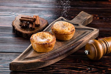Belem 'den zanaatkar hamur işleri, Portekiz' den geleneksel tatlı. Lezzetli ev yapımı Portekiz Pastası - Pasteis de Belem ya da Nata üzerine krema serpiştirilmiş siyah ahşap masa