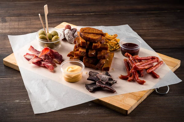 Assortment of beer snacks, chips, dried meat, smoked cheese and sausage on wooden background. Beer Snack Mix plate for oktoberfest