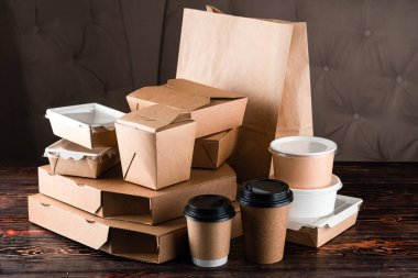 Yemek dağıtım araçları için eko sofra takımını hazırlayın. Eko kağıt sofra takımı. Kağıt bardaklar, tabaklar, torbalar, fast food kutuları, tahta arka planda teslimat için kutular. Geri dönüşüm konsepti. Sıfır atık, plastiksiz ve çevre dostu yaşam