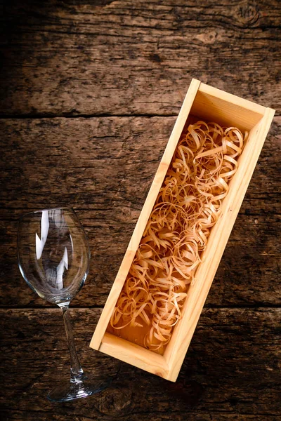 Wine box packaging long wooden box, empty wooden wine crate with shavings and a wine glass