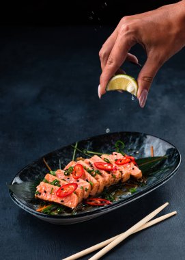 Tütsülenmiş kırmızı balık filetosu, alabalık ya da limon ve mikro yeşillikle servis edilen somon bifteği kadın ellerinde limon dilimleri. Tütsülenmiş somon balıklı brunch tahtası. Sağlıklı yemek.