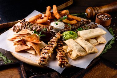 Şiş kebap ve atıştırmalık soğan halkaları ve ahşap tabakta atıştırmalıklar.