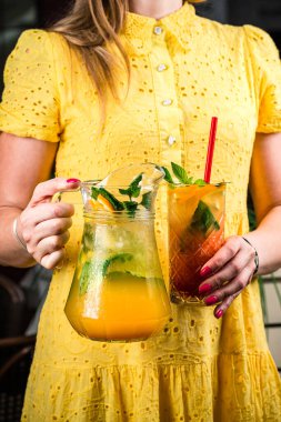Soğuk yaz limonatasını portakallı, greyfurtlu ve naneli kadın elini bir kafede masaya koyup buzlu pembe kokteyl içiyor.